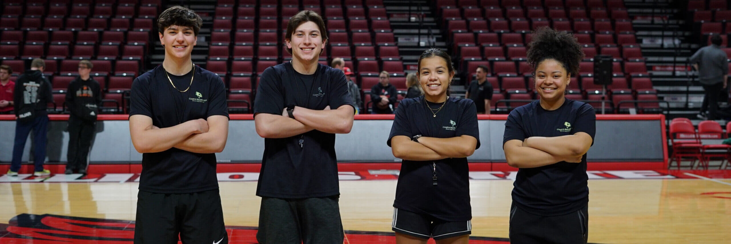 Four student employees pose for a photo on the basketball court.